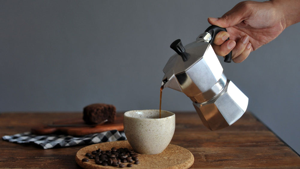 mano che inclina una moka per versare il caffè